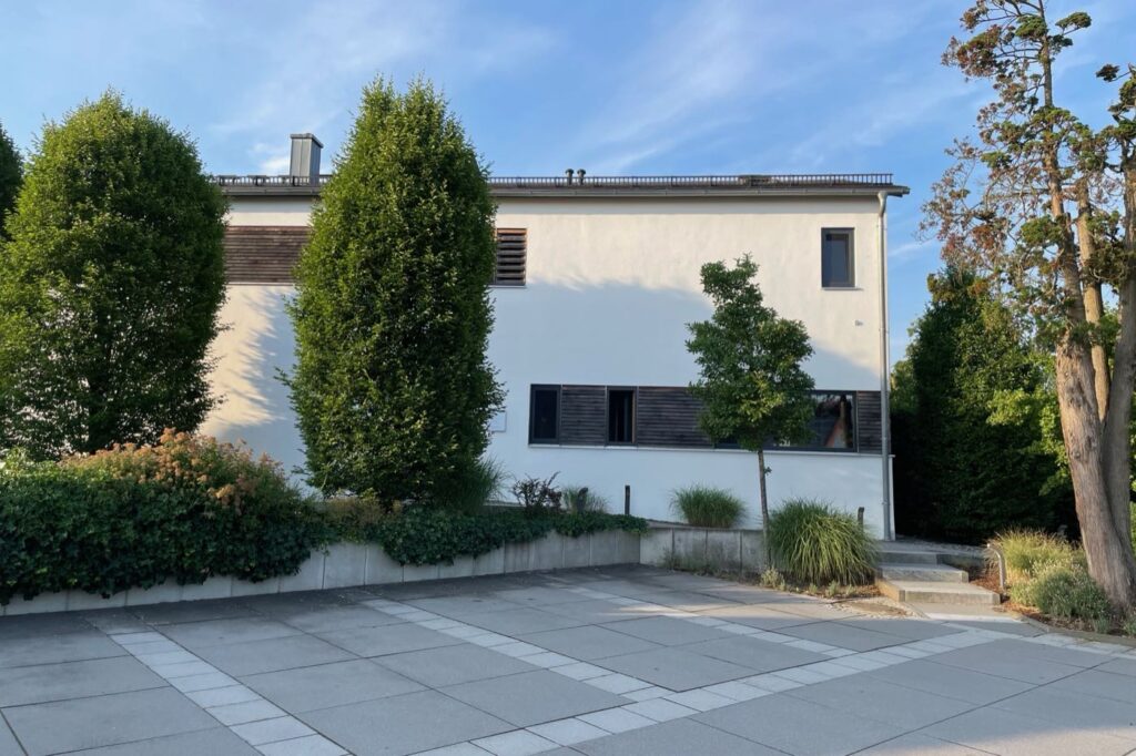 Das Praxisgebäude in Waidhofen mit dem gepflasterten Vorplatz und den Parkplätzen davor